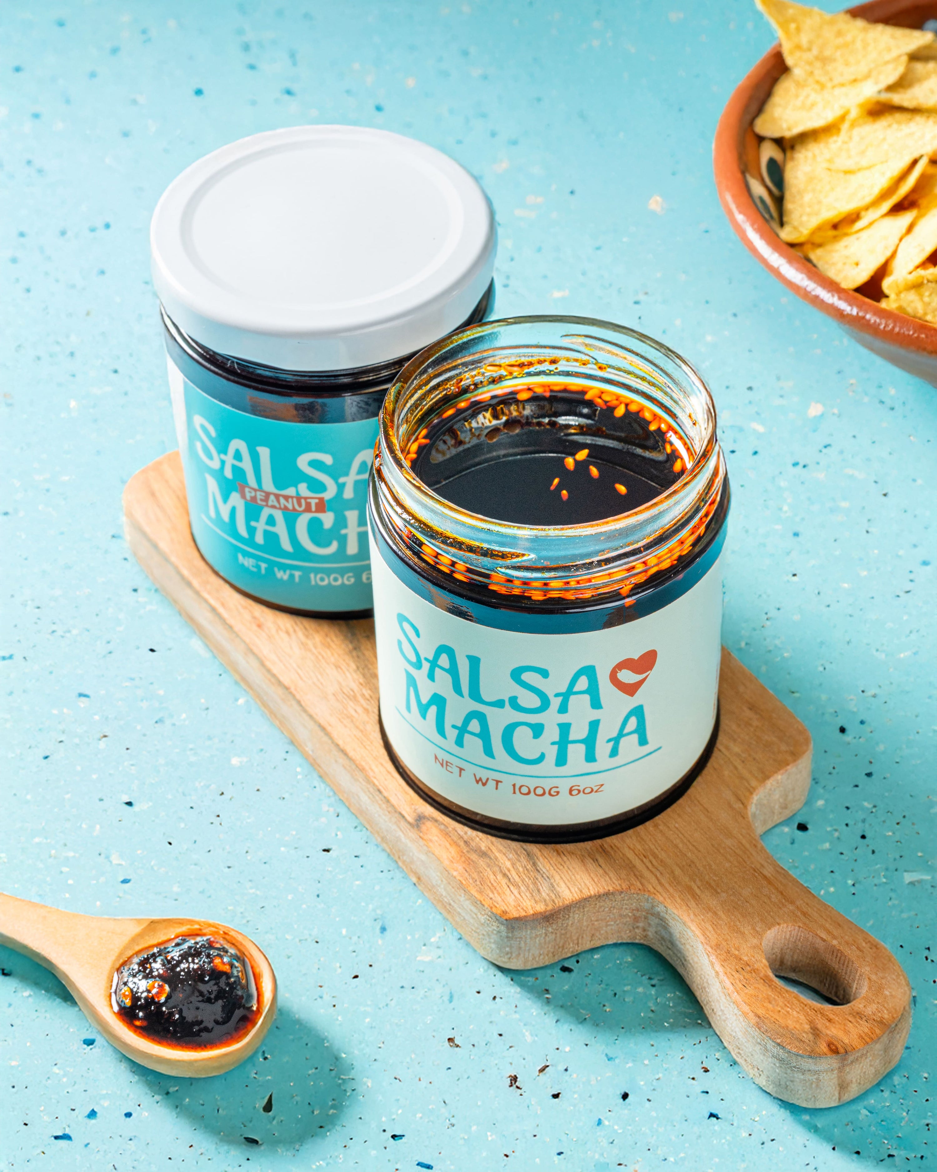Open jar of Veracruz All Natural Salsa Macha on a small wooden board next to tortilla chips